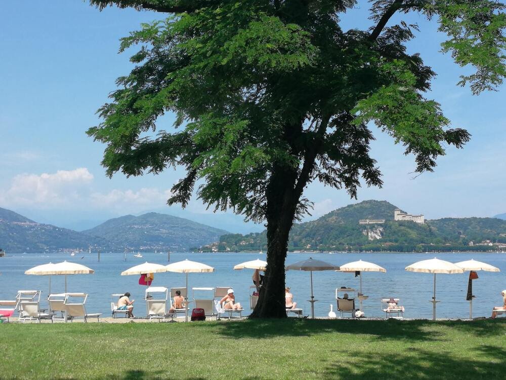 spiaggia attrezzata sul Lago Maggiore in estate con lettini e ombrelloni